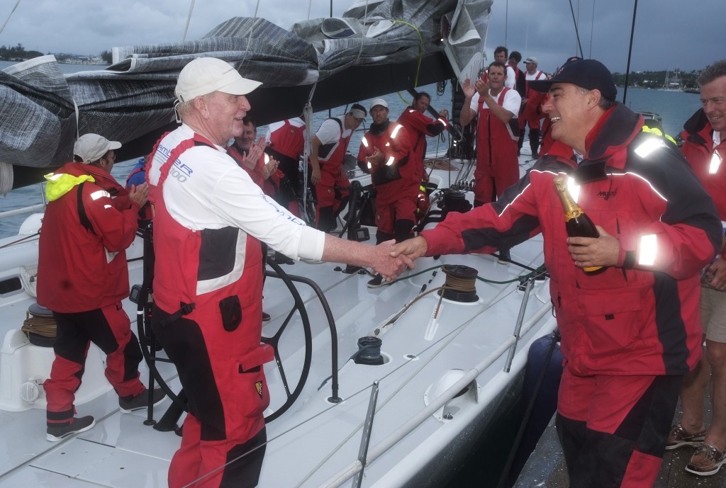 Commodore Jonathan Brewin welcomes George David to Bermuda with a bottle of champagne to celebrate Rambler's record breaking finish. Credit: PPL Media